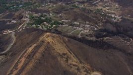 HD stock footage aerial video of flying over a mountain scarred by fire to approach destroyed homes, Malibu, California Aerial Stock Footage | CAP_018_019