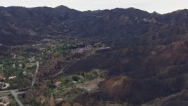 HD stock footage aerial video of approaching homes destroyed by fire by scorched mountains, Malibu, California Aerial Stock Footage | CAP_018_028
