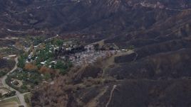 HD stock footage aerial video of flying toward homes destroyed by fire by scorched mountains, Malibu, California Aerial Stock Footage | CAP_018_029