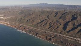 HD stock footage aerial video of panning across I-5 between mountains and coastal cliffs to reveal nuclear plant, San Clemente, California Aerial Stock Footage | CAP_021_045