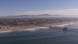 HD stock footage aerial video of flying by a pier and the beach in Huntington Beach, California Aerial Stock Footage | CAP_021_083