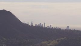 HD stock footage aerial video of the city's skyline on a hazy day, eclipsed by the Hollywood Hills, Downtown Los Angeles, California Aerial Stock Footage | CAP_021_130