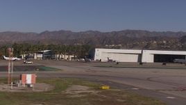 HD stock footage aerial video of civilian jets and helicopters by aviation building and a Burbank Airport hangar, California Aerial Stock Footage | CAP_021_134