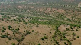 HD stock footage aerial video of approaching a village across a dry river in open savanna, Zimbabwe Aerial Stock Footage | CAP_026_013