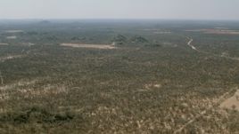 HD stock footage aerial video of flying over savanna toward hills beside fields, Zimbabwe Aerial Stock Footage | CAP_026_061