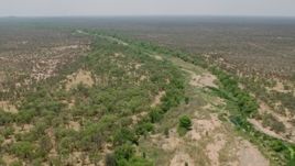 HD stock footage aerial video of flying over a dry riverbed past trees in savanna, Zimbabwe Aerial Stock Footage | CAP_026_075
