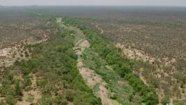 HD stock footage aerial video of following a dry riverbed past trees in savanna, Zimbabwe Aerial Stock Footage | CAP_026_076