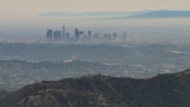 HD aerial stock footage of flying over Verdugo Mountains, by hazy Downtown Los Angeles, California Aerial Stock Footage | CBAX01_117