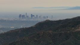 HD aerial stock footage of flying by hazy skyline from Verdugo Mountains, Downtown Los Angeles, California Aerial Stock Footage | CBAX01_118