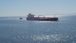 4K aerial stock footage fly low over ocean to approach oil tanker, tugboat, Long Beach, California Aerial Stock Footage | DCA06_032