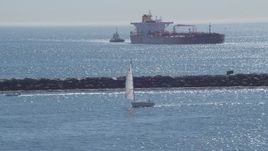 4K aerial stock footage of a sailboat, oil tanker, and tugboat near breakwater, Long Beach, California Aerial Stock Footage | DCA06_034