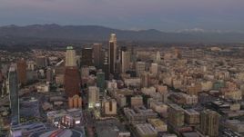 4K aerial stock footage of flying by Downtown skyscrapers, mountains in the distance, Los Angeles, California, twilight Aerial Stock Footage | DCA07_011