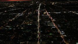 4K aerial stock footage of following Wilshire Blvd through Koreatown and tilt to a wider view of Los Angeles, California, night Aerial Stock Footage | DCA07_066