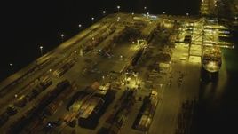 4K aerial stock footage pan across cargo containers, reveal cargo ship, cranes, Port of Long Beach, California, night Aerial Stock Footage | DCA07_144