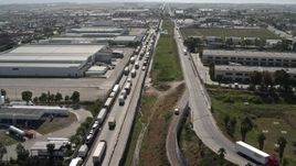 4K aerial stock footage of a line of trucks by warehouses, US/Mexico Border, Tijuana Aerial Stock Footage | DCA08_083E