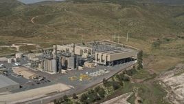 4K aerial stock footage pan across a green field to reveal and orbit a power plant in Otay Mesa, California Aerial Stock Footage | DCA08_095E