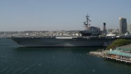 4K aerial stock footage tilt from fishing boats to reveal and orbit an aircraft carrier, the USS Midway, Downtown San Diego, California Aerial Stock Footage | DCA08_196E