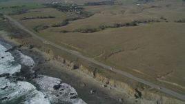 5K aerial stock footage Flyby Highway 1 on the California coast and pan left to ocean waves and an empty beach, San Simeon, California Aerial Stock Footage | DCSF03_016