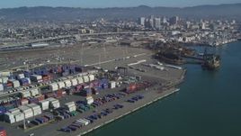 5K aerial stock footage Flyby cargo cranes, containers, cargo ships at Port of Oakland, Downtown Oakland in the background, California Aerial Stock Footage | DCSF05_079