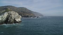 5K aerial stock footage orbit a large rock formation off the coast, reveal coastal cliffs, Big Sur, California Aerial Stock Footage | DFKSF03_095