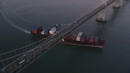 5K aerial stock footage of a cargo ship sailing under Bay Bridge, San Francisco, California, sunset Aerial Stock Footage | DFKSF10_051