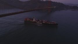 5K aerial stock footage of a cargo ship sailing under Golden Gate Bridge, San Francisco, California, twilight Aerial Stock Footage | DFKSF14_043