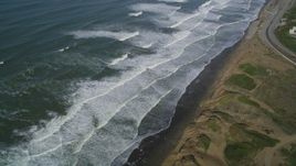5K aerial stock footage of waves rolling toward coastal cliffs in the Lakeshore District, San Francisco, California Aerial Stock Footage | DFKSF15_045