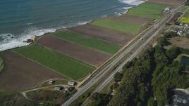 5K aerial stock footage of flying away from Highway 1 along the coast and crop fields, Davenport, California Aerial Stock Footage | DFKSF15_113