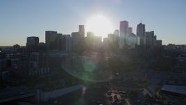 5.7K aerial stock footage of passing the rising sun behind the city skyline in Downtown Denver, Colorado Aerial Stock Footage | DX0001_001629
