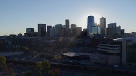 5.7K aerial stock footage flyby the rising sun behind the city skyline, reveal the arena in Downtown Denver, Colorado Aerial Stock Footage | DX0001_001631