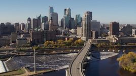 5.7K aerial stock footage descend by the skyline, seen from a bridge spanning the river in Downtown Minneapolis, Minnesota Aerial Stock Footage | DX0001_002140