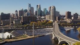 5.7K aerial stock footage descending by a bridge spanning the river with a view of the skyline, Downtown Minneapolis, Minnesota Aerial Stock Footage | DX0001_002144
