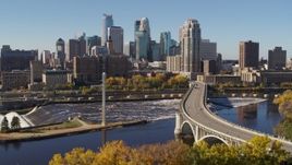 5.7K aerial stock footage flying by a bridge spanning the river and ascend, with a view of the skyline, Downtown Minneapolis, Minnesota Aerial Stock Footage | DX0001_002145