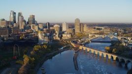 5.7K aerial stock footage passing bridge and river to reveal power plant, with view of skyline at sunrise, Downtown Minneapolis, Minnesota Aerial Stock Footage | DX0001_002300