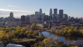 5.7K aerial stock footage ascend from trees to flyby the city's skyline, reveal the river, Downtown Minneapolis, Minnesota Aerial Stock Footage | DX0001_002360