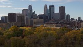 5.7K aerial stock footage descend near trees with view of towering skyscrapers of the city skyline, Downtown Minneapolis, Minnesota Aerial Stock Footage | DX0001_002382