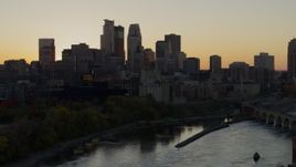 5.7K aerial stock footage descend by river with view of city skyline in background at sunset, Downtown Minneapolis, Minnesota Aerial Stock Footage | DX0001_002540