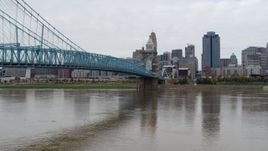 5.7K aerial stock footage descend by the Roebling Bridge spanning Ohio River with view of the city skyline, Downtown Cincinnati, Ohio Aerial Stock Footage | DX0001_002641