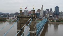 5.7K aerial stock footage orbit flags on the Roebling Bridge spanning Ohio River, with view of the city skyline, Downtown Cincinnati, Ohio Aerial Stock Footage | DX0001_002642
