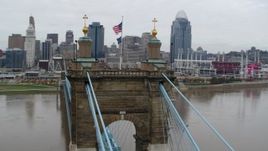 5.7K aerial stock footage orbit flags on top of the Roebling Bridge, with view of the city skyline, Downtown Cincinnati, Ohio Aerial Stock Footage | DX0001_002643