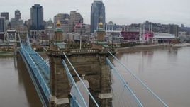 5.7K aerial stock footage orbit flags on top of the Roebling Bridge, reveal the city skyline, Downtown Cincinnati, Ohio Aerial Stock Footage | DX0001_002644