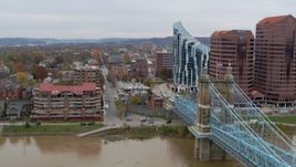 5.7K aerial stock footage flyby Roebling Bridge near condo complex and office buildings in Covington, Kentucky Aerial Stock Footage | DX0001_002653