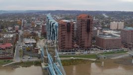 5.7K aerial stock footage following Roebling Bridge past office buildings to approach condo complex in Covington, Kentucky Aerial Stock Footage | DX0001_002661