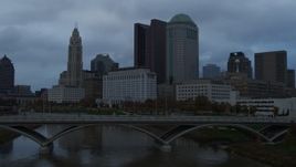 5.7K aerial stock footage ascend from bridge for view of the city skyline and the Scioto River at sunset, Downtown Columbus, Ohio Aerial Stock Footage | DX0001_002749