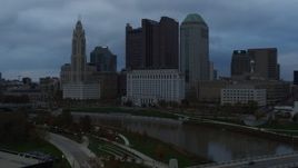 5.7K aerial stock footage flying by the city skyline and the Scioto River at sunset, descend to reveal bridge, Downtown Columbus, Ohio Aerial Stock Footage | DX0001_002751