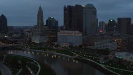 5.7K aerial stock footage of flying by the city skyline and the Scioto River at sunset, Downtown Columbus, Ohio Aerial Stock Footage | DX0001_002754