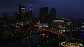 5.7K aerial stock footage of passing by the city's skyline across a bridge and river at twilight, Downtown Columbus, Ohio Aerial Stock Footage | DX0001_002787