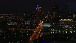 5.7K aerial stock footage of passing by the city skyline, and bridge spanning the river at night, Downtown Columbus, Ohio Aerial Stock Footage | DX0001_002799