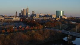 5.7K aerial stock footage of the city's skyline at sunset seen from White River, ascend over bridge, Downtown Indianapolis, Indiana Aerial Stock Footage | DX0001_002925