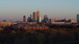 5.7K aerial stock footage descend behind trees with wide view of the city's downtown skyline at sunset, Downtown Indianapolis, Indiana Aerial Stock Footage | DX0001_002936